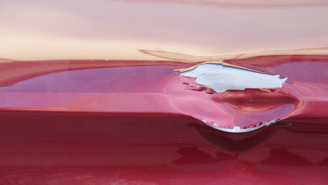 Red car with dents and peeling paint