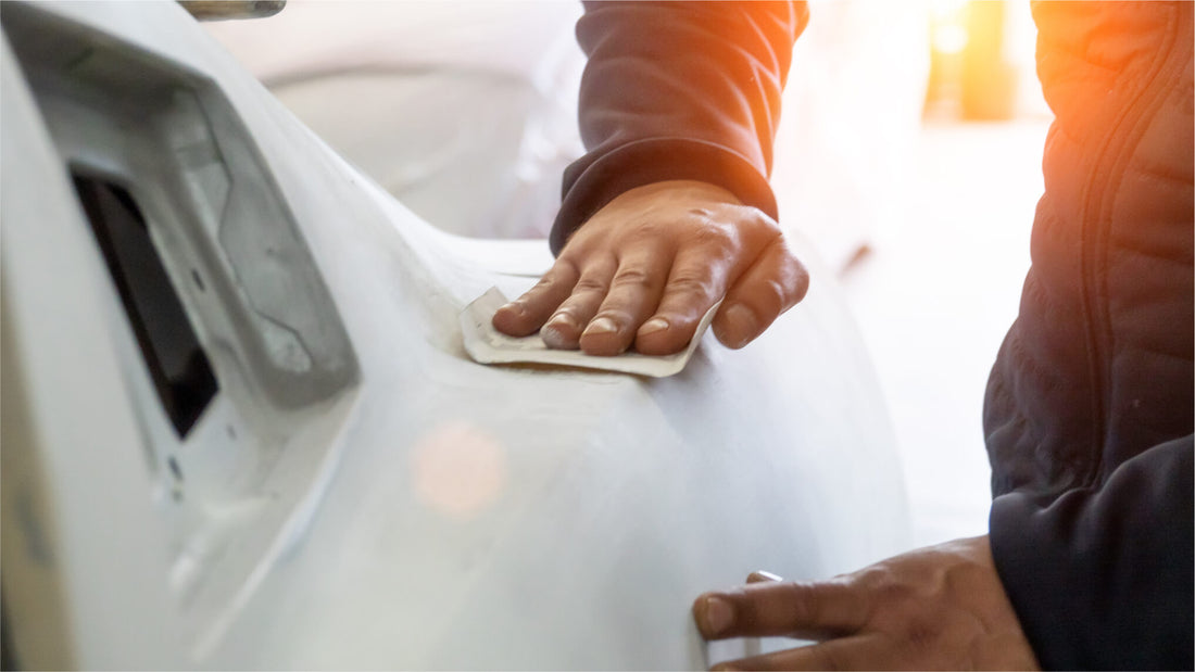 Ein Mann reinigt ein weißes Auto mit der Hand