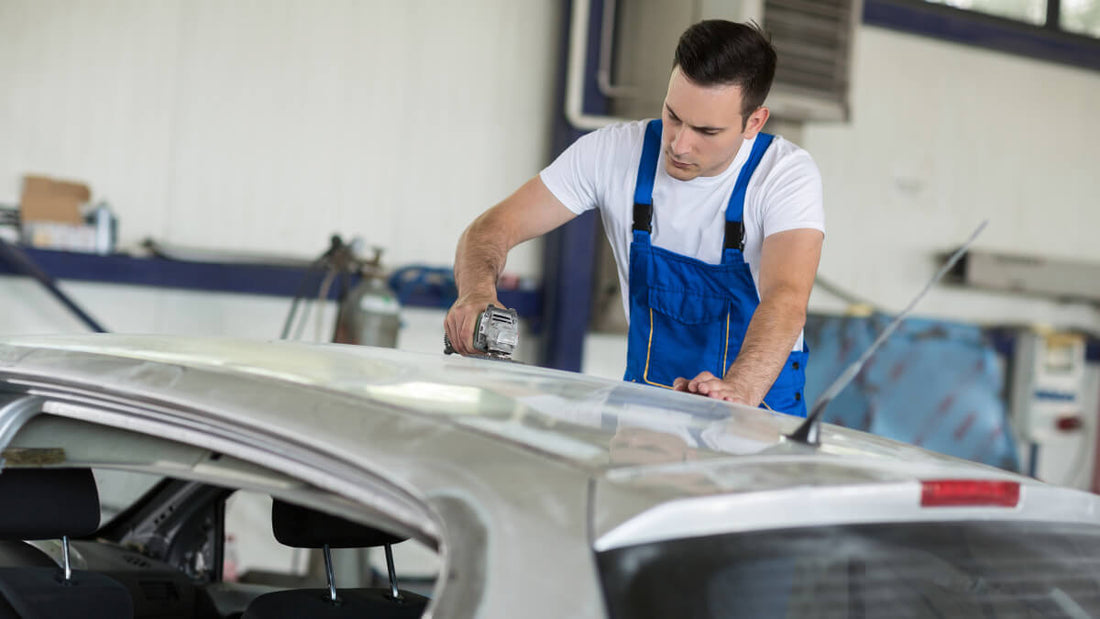 Ein Mechaniker schleift ein Autoteil in einer Autowerkstatt
