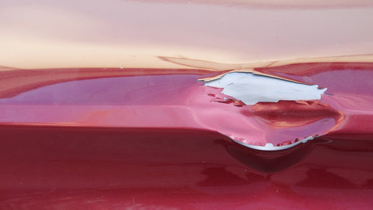 Red car with dents and peeling paint