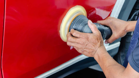 Ein Mechaniker poliert das rote Auto