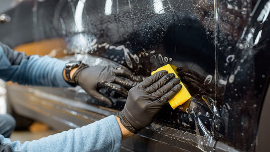 Der Mann mit den schwarzen Handschuhen putzt das Auto