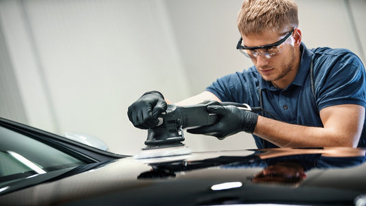 Ein Automechaniker poliert ein schwarzes Auto